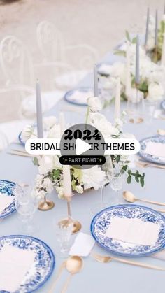 the table is set with blue and white plates, silverware, flowers and candles