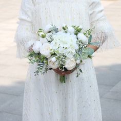 a woman holding a bouquet of white flowers