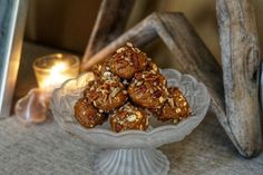 a glass bowl filled with granola and nuts next to a candle on a table