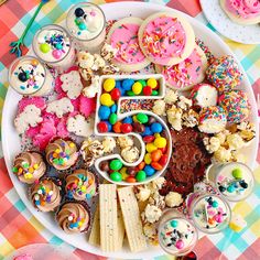 a white plate topped with lots of cupcakes and cake covered in sprinkles