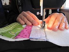 a person is using a sewing machine to sew on some cloths that have been stitched together