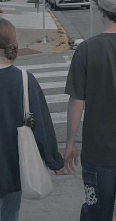 two people walking down the street holding hands