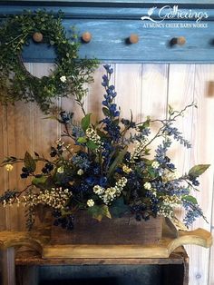 a vase filled with blue flowers sitting on top of a wooden table next to a fireplace