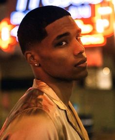 a young man standing in front of a neon sign