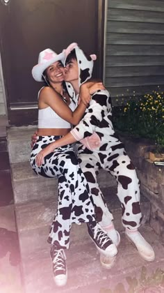 two people dressed up like cows sitting on steps with their heads wrapped around each other