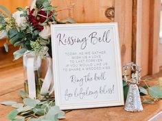 a sign that says kissing bell next to some flowers and an angel figurine