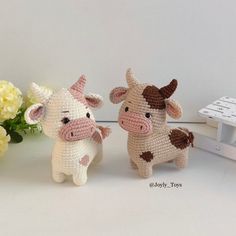 two small crocheted cows standing next to each other