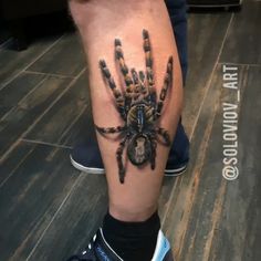 a man's leg with a tattoo on it that has a spider crawling in the center