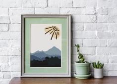 an art print on a wall next to a potted plant and a framed photograph