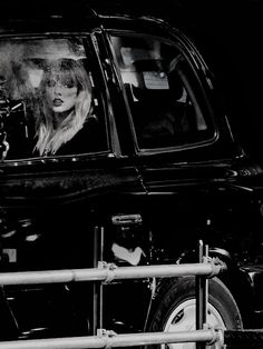 a black and white photo of a woman in a car