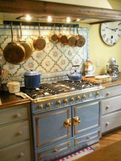 an old fashioned kitchen with pots and pans hanging on the wall above the stove