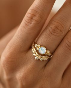 a woman's hand wearing a gold ring with an oval shaped ruby and diamond band