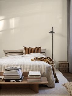 a bed sitting next to a table with books on top of it in a bedroom