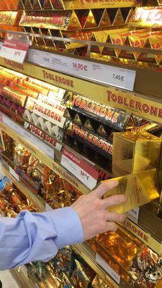 a person reaching out to grab something from a shelf in a store that is filled with gold and other items