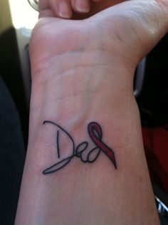 a small wrist tattoo with the word love and a red ribbon on it's wrist