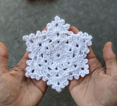 two hands holding a small white crocheted object