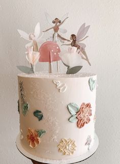 there is a cake decorated with flowers and fairy figurines on top of it