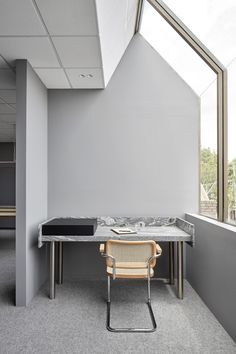 a chair and table in an office with skylights on the windows sill above