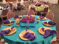 the table is set with purple and yellow plates, silverware, and napkins