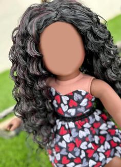 a doll with long black hair and red hearts on it's dress is standing in the grass