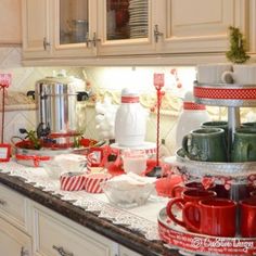 the kitchen counter is covered with red and white plates, cups, and mugs