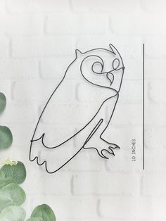 the outline of an owl sitting on top of a white brick wall next to green leaves