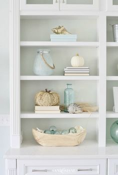 a white bookcase filled with books and vases