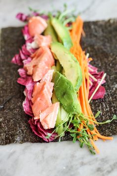 some food is laying out on the ground with lettuce, carrots and avocado