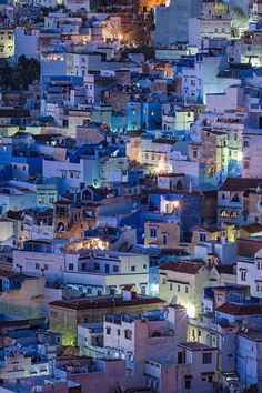 an aerial view of a city at night with buildings lit up in blue and white