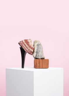 a pair of high heeled shoes sitting on top of a block of wood and stone