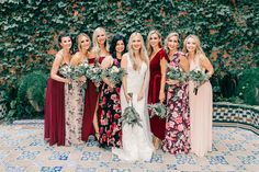 a group of women standing next to each other in front of a wall covered with ivy