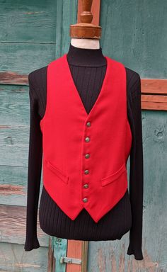 This handsome vest will set off your weekend riding attire so well, with a brilliant flash of bright color and lovely tailoring. Red worsted wool front with acetate lining/back; 6 button front placket, faux cuffed front pockets, deep v-neck, strap/buckle adjustment back, excellent condition. No label or marked size but measures like a 40, c1960s. The following measurements were taken with the garment lying FLAT and recorded in inches, please be sure and DOUBLE the appropriate measurements: Shoul Classic Red Winter Vest, Fitted Red Vest With Buttons, Classic Wool Vest With Button Closure, Classic Red Vest For Fall, Red Wool Vest For Winter, Classic Red Vest For Workwear, Vintage Wool Vest For Formal Occasions, Classic Red Sleeveless Outerwear, Classic Red Sleeveless Vest