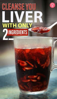 a glass pitcher filled with red liquid on top of a table next to a spoon