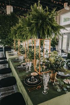 a long table set with place settings and greenery