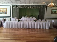 a long table is set up with white linens and flower centerpieces for a formal function