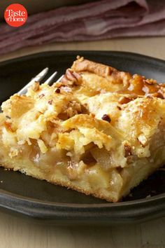 a piece of pie on a black plate with a fork and napkin next to it