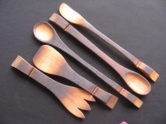 four wooden spoons are lined up next to each other on a black tablecloth