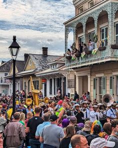 a large group of people standing in front of a building with lots of windows and balconies