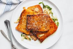 two pieces of french toast on a white plate with silverware next to the plate