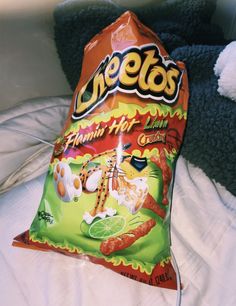 a bag of cheetos sitting on top of a bed next to a stuffed animal