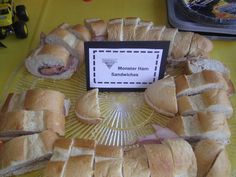 a platter filled with sandwiches on top of a yellow table covered in plastic wrappers