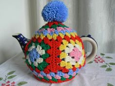 a crocheted tea pot with a blue pom - pom on top