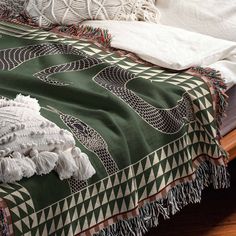 a green and white bedspread with tassels on the edges, sitting on a wooden bed