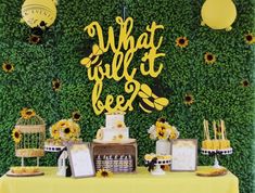 a table with sunflowers, cake and balloons on it that says what will bee?