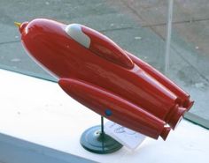 a red toy rocket ship on display in a window sill next to a sidewalk