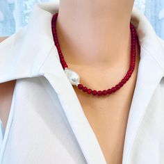 Add a splash of vibrant color to your collection with this beautiful red coral short necklace. Featuring striking red coral beads, this necklace exudes a bold, natural beauty that instantly elevates any look. A unique natural baroque pearl placed on the side adds an elegant focal point, creating a stunning contrast against the vibrant coral. Crafted with sterling silver details, this necklace has a polished, luxurious finish. At 18 inches, it sits comfortably along the neckline, making it perfec Handmade Red Coral Pearl Necklace, Elegant Red Beaded Necklace With Lobster Clasp, Red Coral Necklace, Coral Shorts, Coral Necklace, Coral Beads, Short Necklace, Formal Outfit, Red Coral