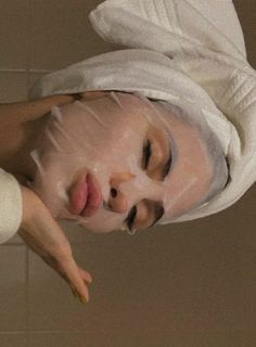 a woman wearing a white towel on top of her head and holding a yellow object in front of her face