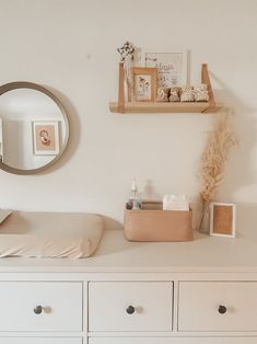 a baby crib and dresser in a white room with a mirror on the wall