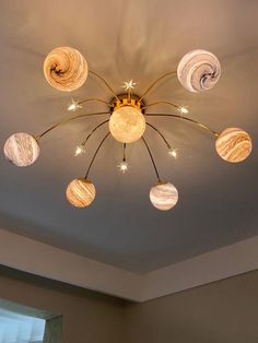 a chandelier with eight lights hanging from it's center and six planets on the ceiling