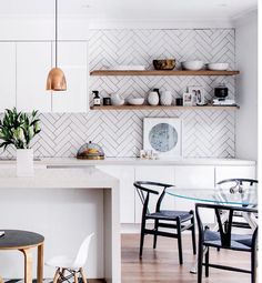 the kitchen is clean and ready to be used for dinner or breakfast time, with white cabinets and herringbone tile on the walls